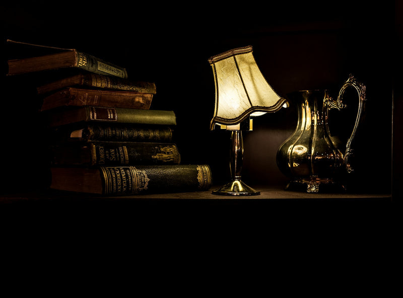 Turned-on desk lamp beside a pile of books in warm light