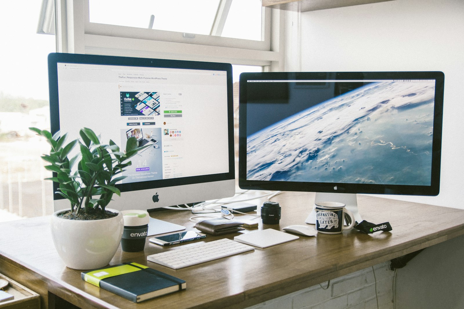 Dual monitor setup raised on arms over a clean brown wood desk