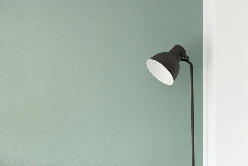 Minimalist floor lamp standing in a quiet corner against a plain wall