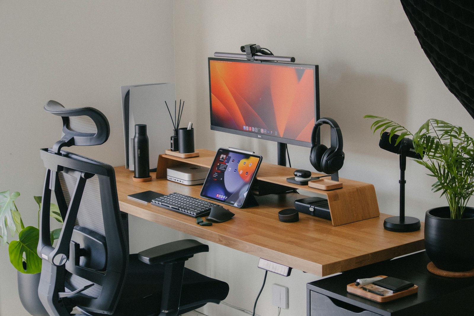 Minimalist wooden desk with a single monitor and keyboard against a clean wall