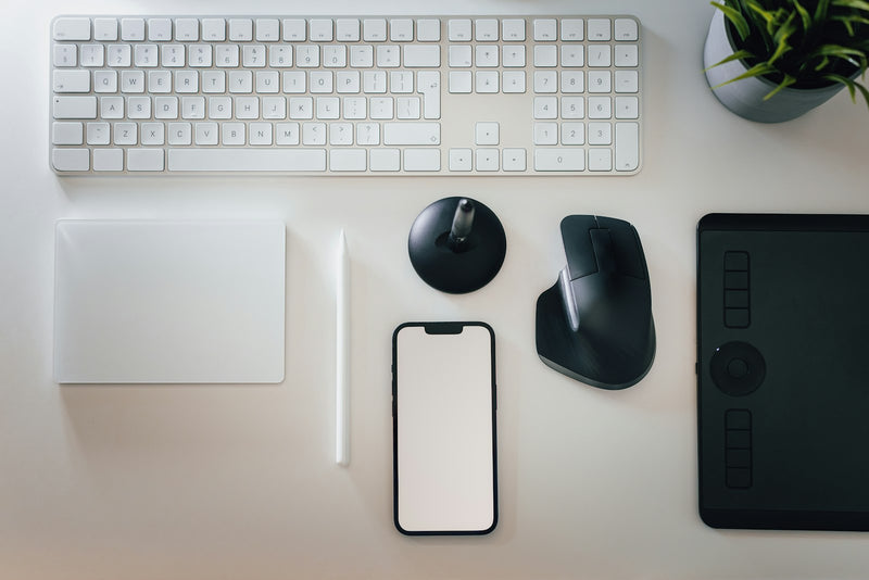 Tidy desk with a keyboard, mouse, phone, and a small plant