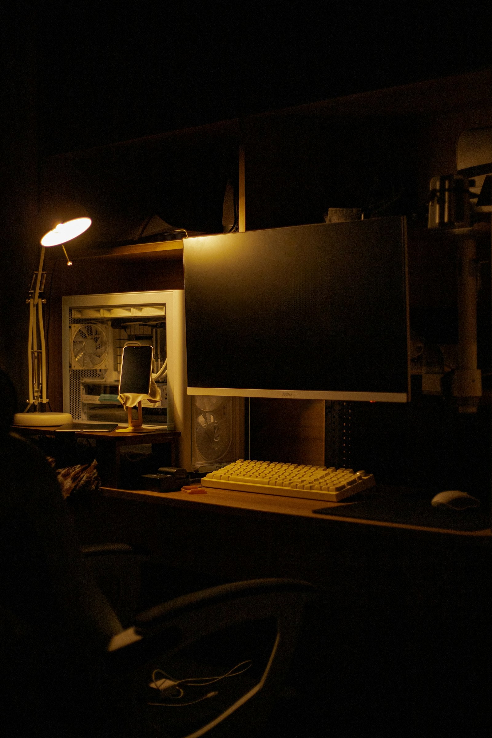 Computer monitor and keyboard on a desk lit softly in a dark room