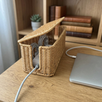 Square-end woven cable box on a home-office desk, lid open over a hidden power strip