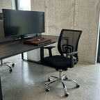 Black mesh task chair in a modern coworking pod